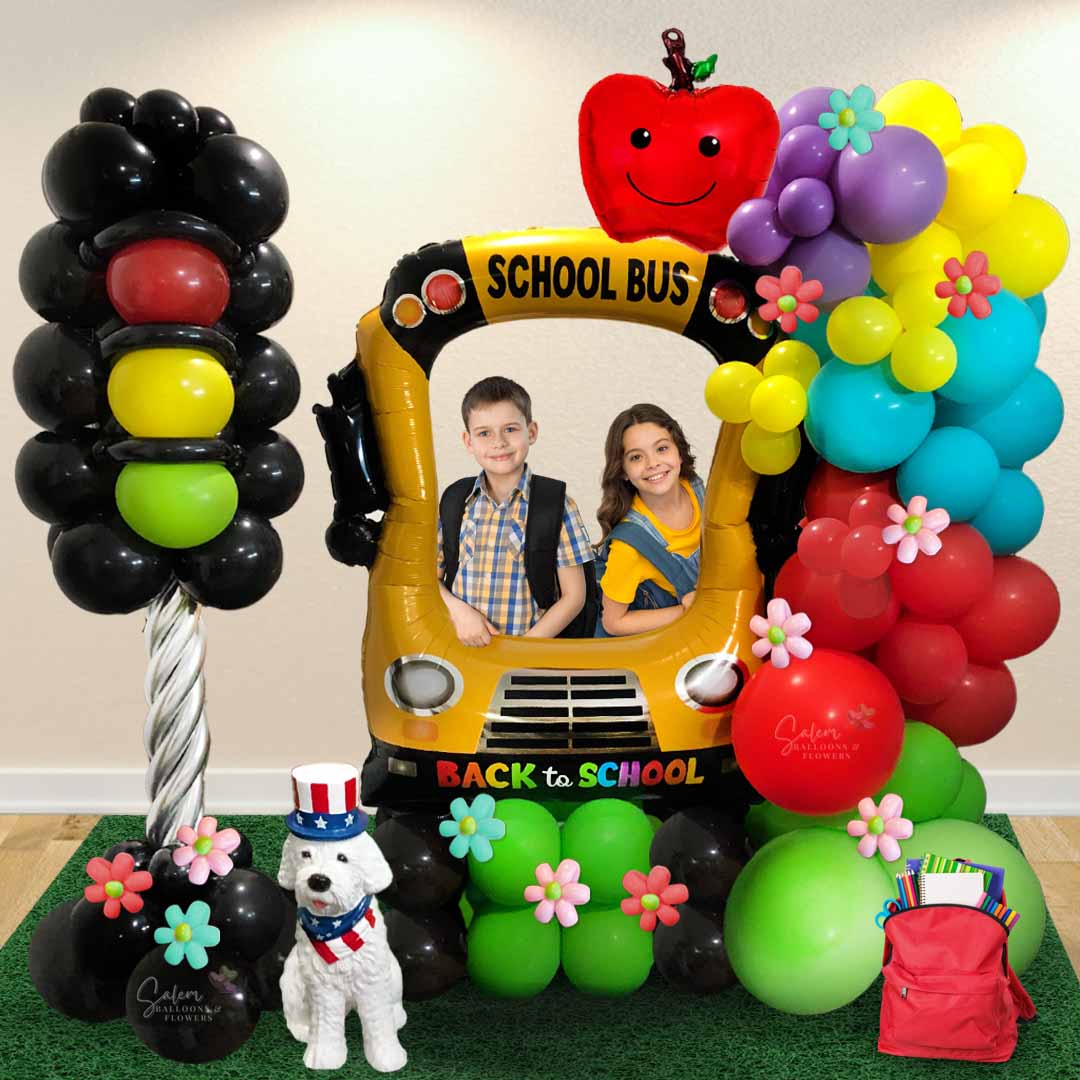 Back to school themed balloon decoration. Featuring an extra large school bus balloon, a traffic light and a balloon garland. Decorated with grass rug, and a doggy prop. Balloon decor Salem-Keizer Oregon