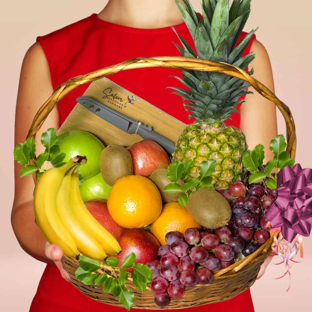 Woman holding a large fruit basket decorated with greenery and cutting board and knife. Fruit baskets Salem Oregon and nearby cities.