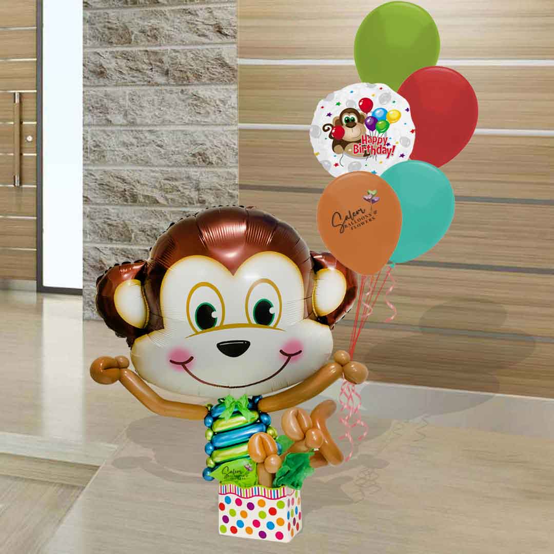 A balloon Monkey in a box holding a set of Birthday helium balloons. Salem Oregon balloon delivery.  3 Ft tall approx.
