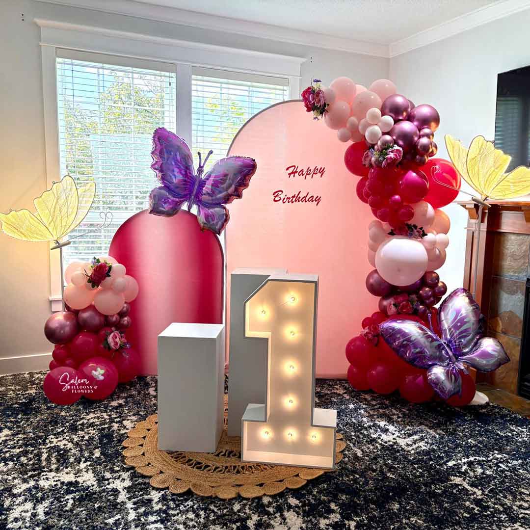 Butterfly-themed Balloon Decoration. 2 Panels, 2 garlands, 2 cake stands and one 1 light up Marquee Number and 2 lit butterflies. In a pink color palette. Balloon Decor. Oregon.