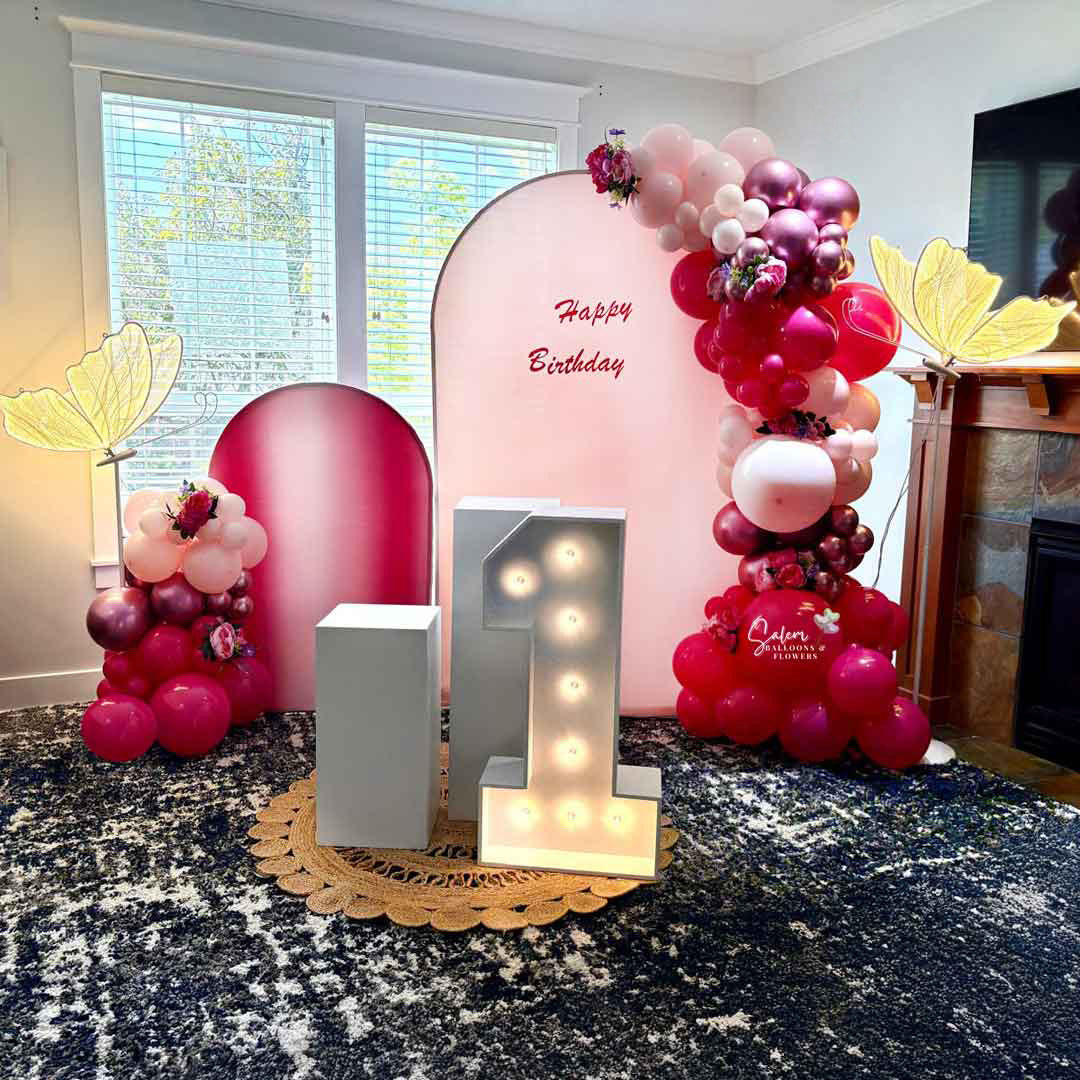 Butterfly-themed Balloon Decoration. 2 Panels, 2 garlands, 2 cake stands and one 1 light up Marquee Number and 2 lit butterflies. In a pink color palette. Balloon Decor. Oregon.