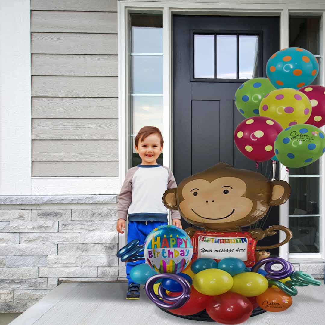a Boy standing next to a Large Balloon Bouquet with colorful balloons, featuring a Monkey balloon with a whiteboard ready for you to write your message. Delivery in Salem Oregon and nearby areas.