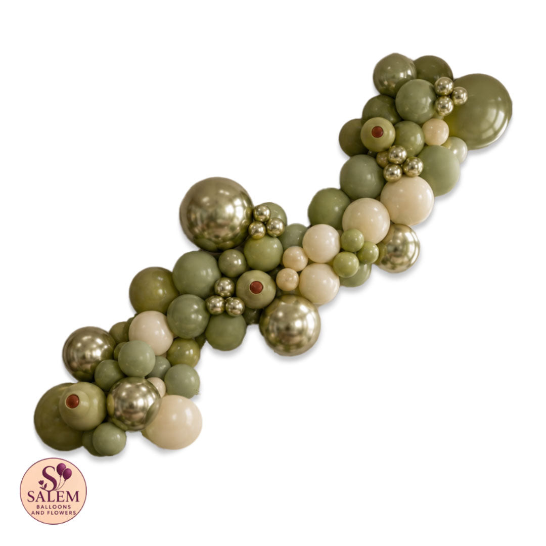 A decorative balloon garland made of olive green, sage green, cream, and metallic gold latex balloons, arranged in a diagonal line on a white background with a Salem Balloons and Flowers logo in the bottom-left corner.