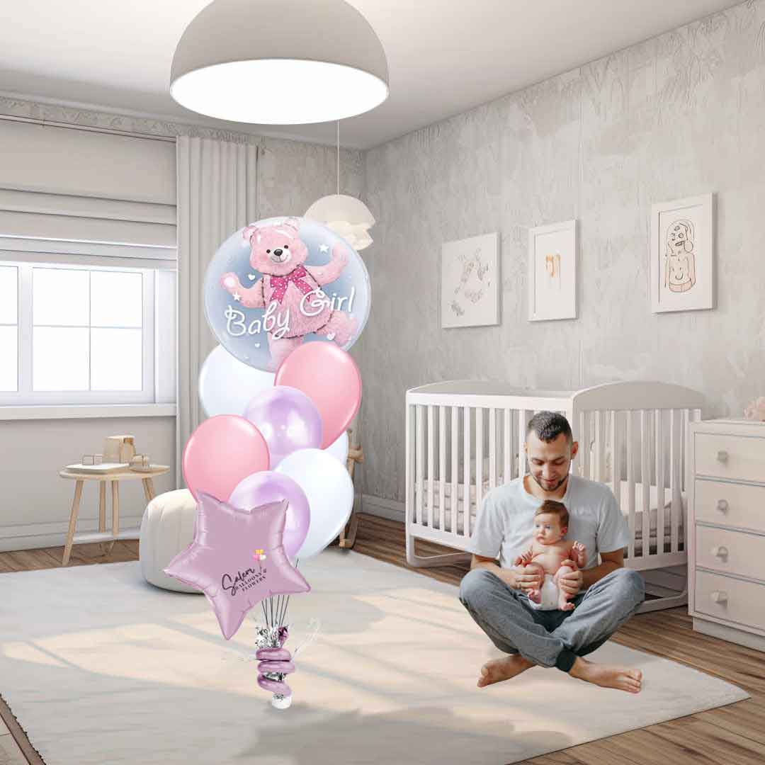 Dad sitting with his baby girl next to a Baby Girl helium classic balloon bouquet. Featuring an extra large stuffed bubble balloon with a teddy bear balloon, and a set of matching colors helium balloons, anchored to a decorated weight. Delivery in Salem Oregon and nearby areas. 