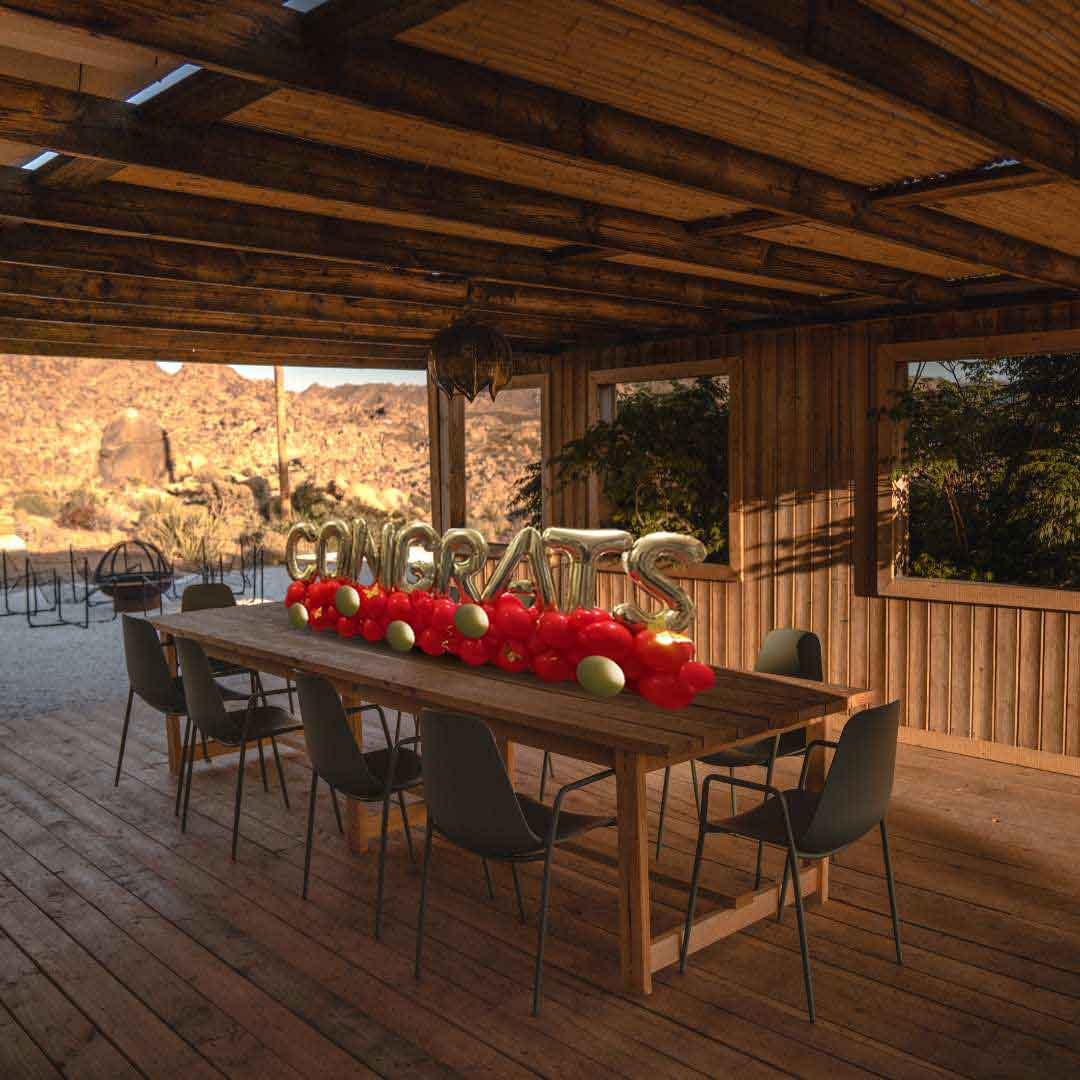A Balloon table runner spelling CONGRATS with gold balloon letters on a balloon garland on a table in a covered patio. Salem Oregon Balloon decor delivery