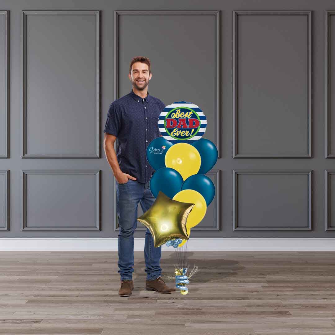 A dad standing next to a Father's Day balloon bouquet. Featuring a Father's Day Mylar balloon with a "Best Dad Ever" message in blue and yellow. Salem Oregon balloon delivery.