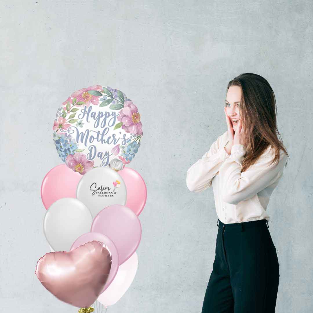 Mom standing surprised next to a Mother's Day Balloon Bouquet in pastel colors and flower prints with a Happy Mother's Day message. Salem Oregon balloon delivery. 