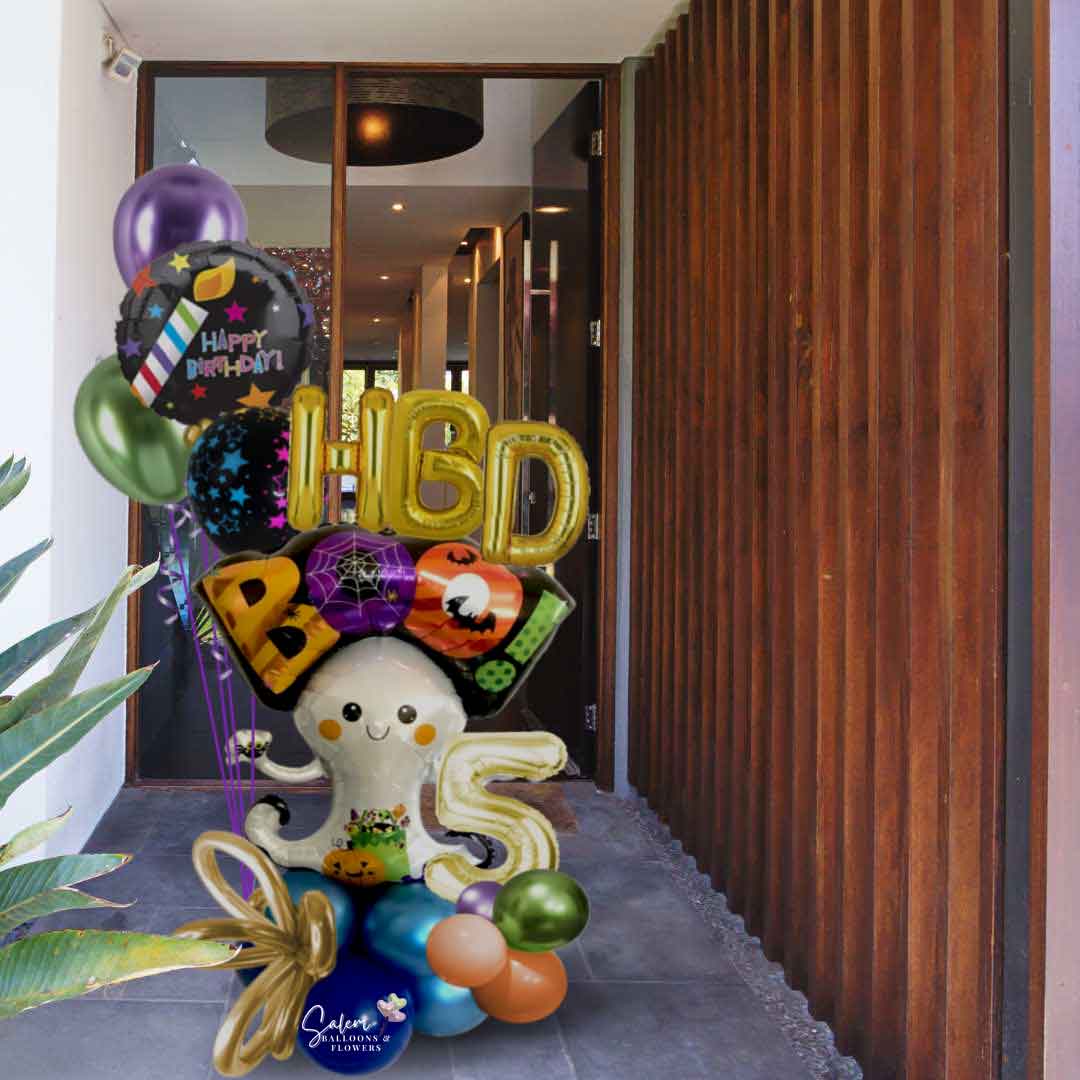 A Halloween-themed birthday bouquet featuring a large ghost balloon carrying an "HBD Boo" sign, floating over a colorful balloon cloud and a bouquet of helium balloons standing in a door entre. Balloon Salem Oregon.