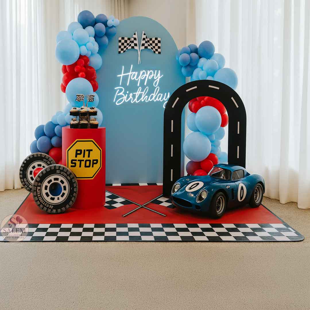 Birthday party setup with race car theme, balloon garlands, car cutouts, tires, and decorations. Balloon decor Oregon.