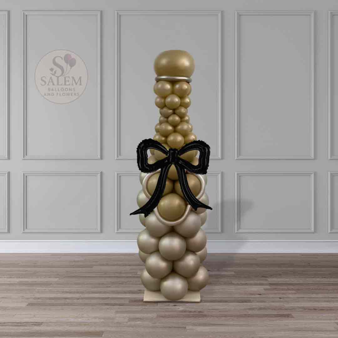Champagne-inspired balloon column with gold balloons and black bow, luxury balloon decor by Salem Balloons and Flowers in Oregon.