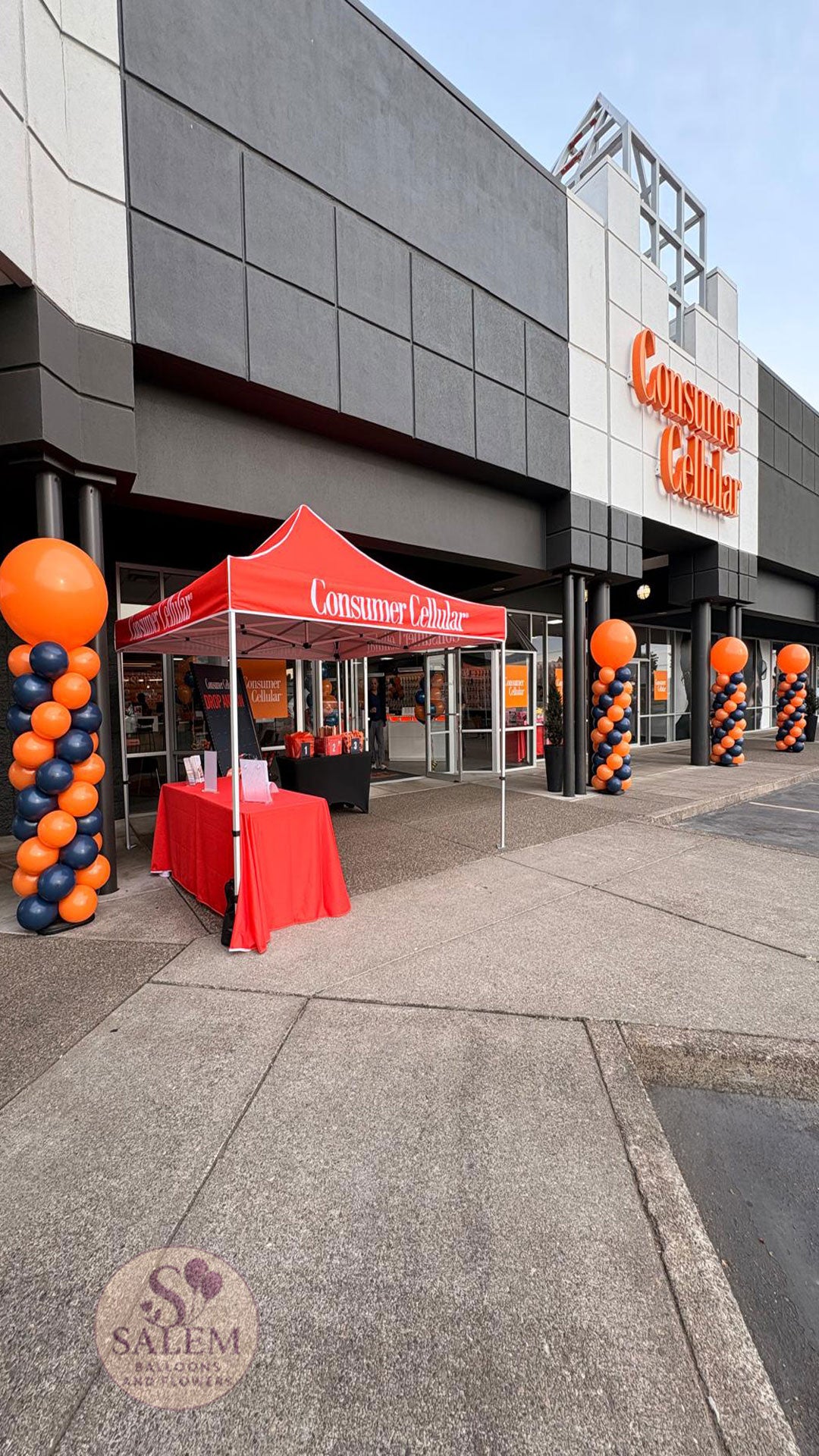 8 ft tall Round top balloon columns in navy blue and orange for the grand opening of the  Consumer Cellular 100 store in Salem Oregon by Salem Balloons and Flowers. Storefront Visibility. 