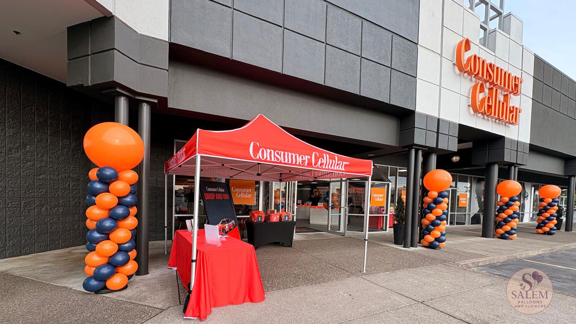 8 ft tall Round top balloon columns in navy blue and orange for the grand opening of the  Consumer Cellular 100 store in Salem Oregon by Salem Balloons and Flowers. Storefront Visibility. 