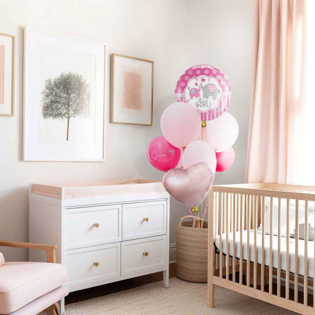 A baby girl nursery room decorated with a "It's a Girl" Helium-filled balloon bouquet in various shades of pink.  Featuring a Mylar balloon with a pink and a gray elephants. Oregon Balloon delivery.