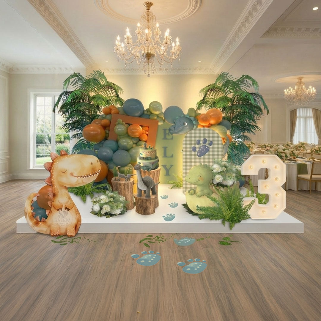 Dinosaur birthday balloon decor with themed backdrop, balloon garland, cake display, greenery and palm trees, and marquee number 3 by Salem Balloons and Flowers Serving  Salem to Portland Oregon.
