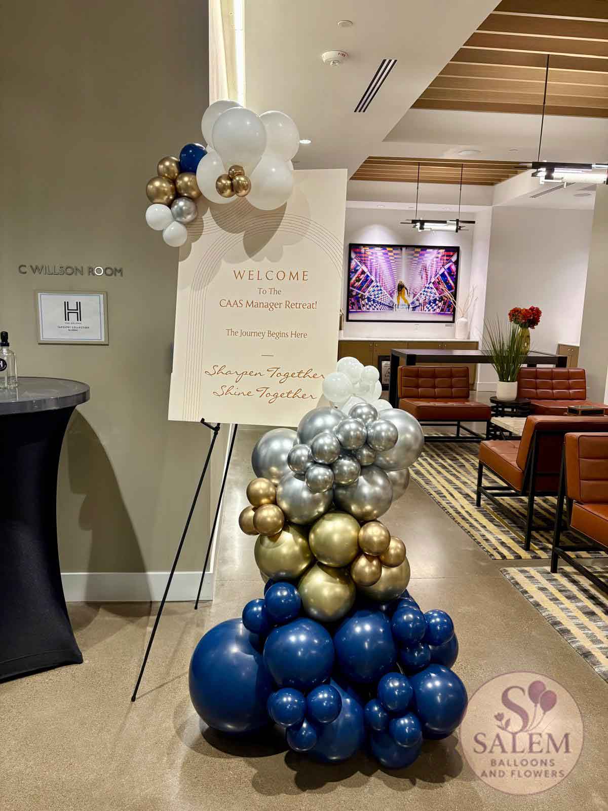 Decorative balloon garland with a welcome sign in a room setting, featuring balloons in blue, gold, and silver. Balloon decor Oregon.