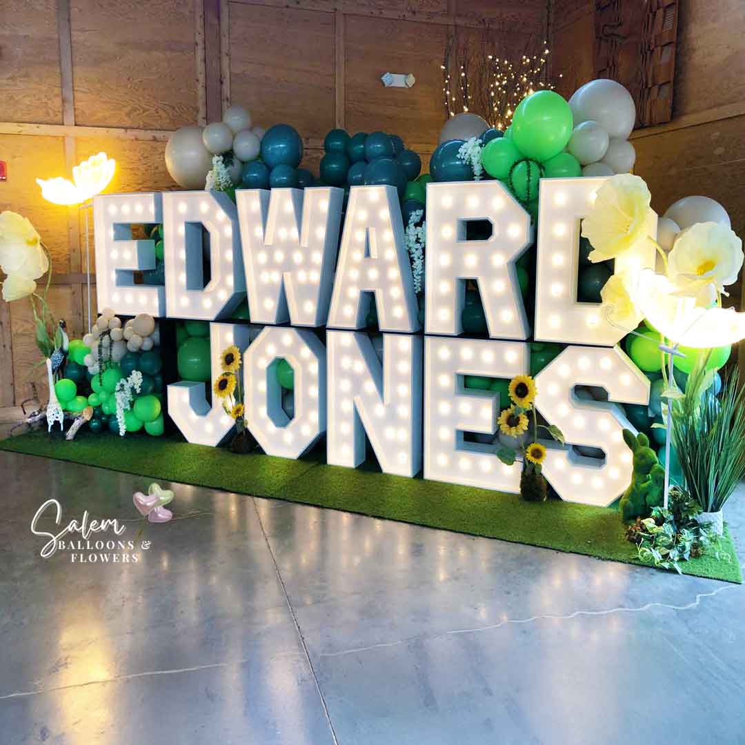 18 ft long x 9 Ft tall 2-story Light up marquee Letter Display with Balloon Decor, giant flowers and birds and lit butterflies. Spelling Edward Jones. Marquee Letter rental and Balloon decor service. Oregon.