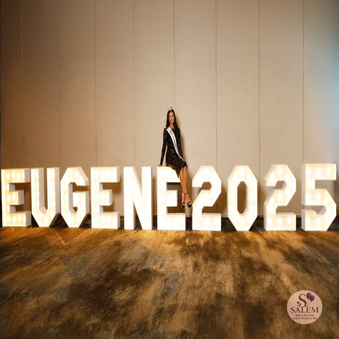 Marquee Letter display spelling Eugene 2025 with miss Oregon posing sitting on Marquee E at the Graduate hotel by Hilton at the Eugene Community's choice awards ceremony 2025. By Salem Balloons and Flowers.