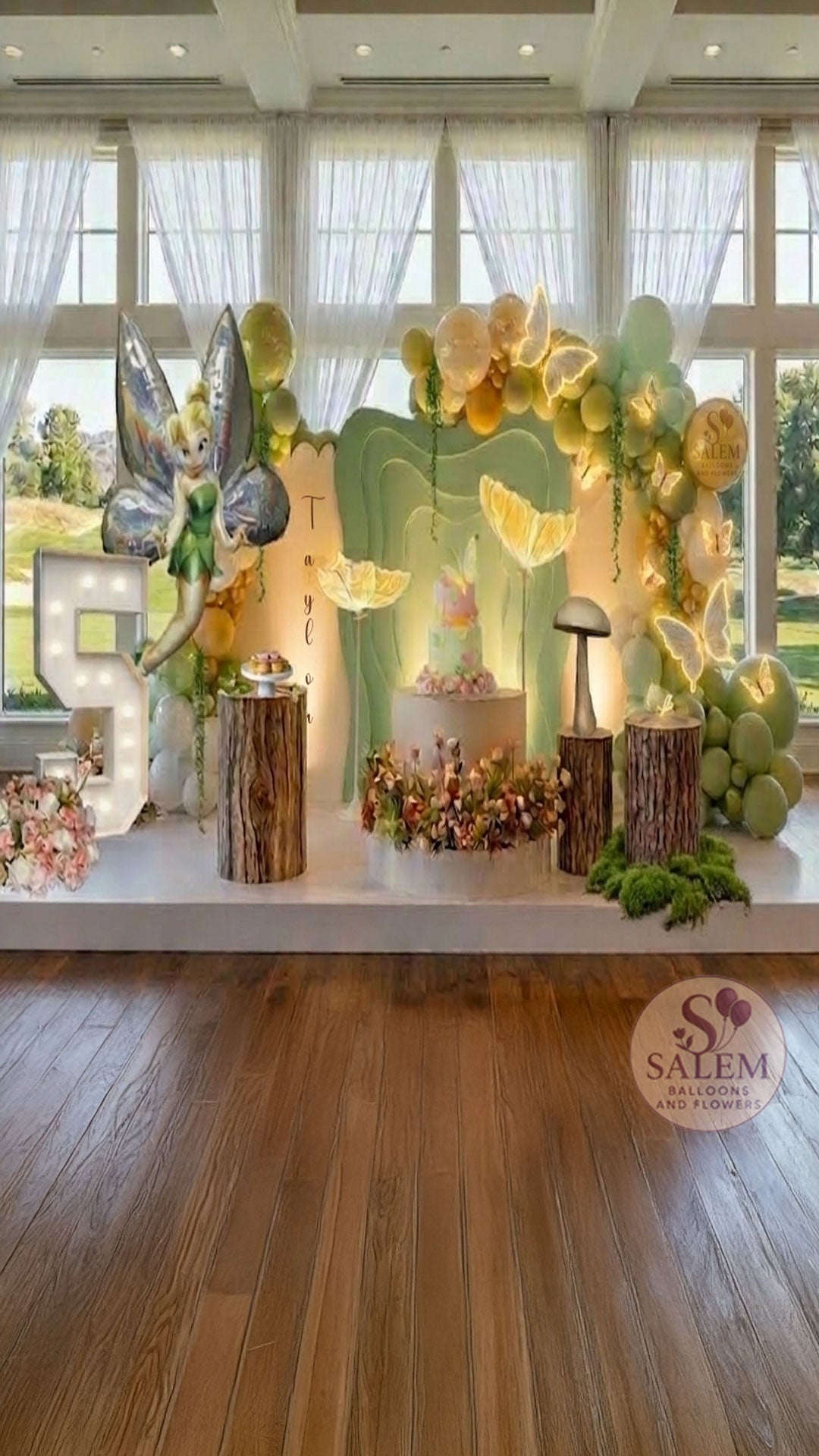 Fairy themed balloon decoration with 3 panels and balloon decor with lit butterflies, decorated with flowers and balloon garlands, lit Marquee number 5 in a room with large windows. Luxury balloon decor. Oregon.
