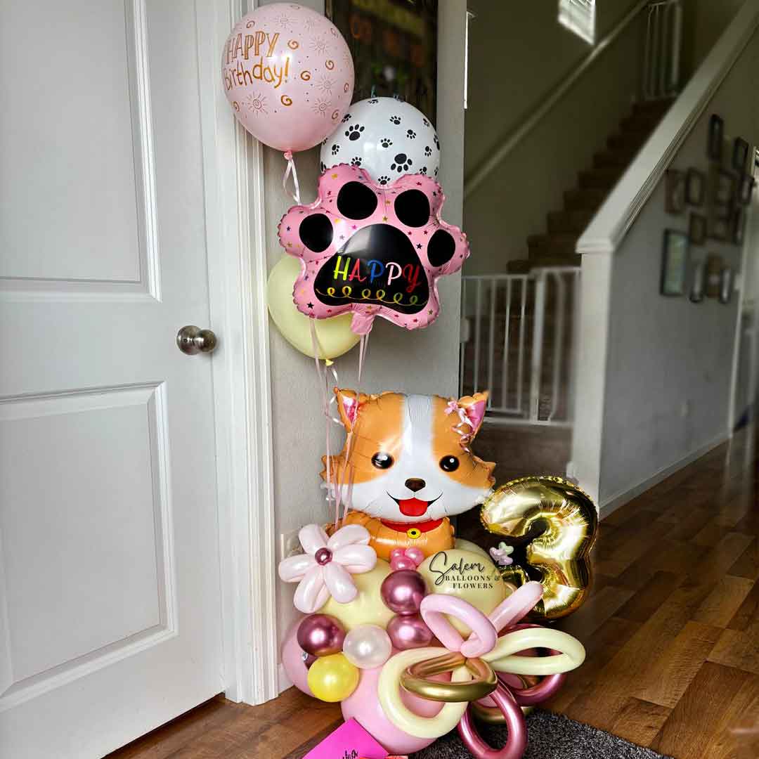 Dog themed birthday balloon bouquet. In pastel colors featuring a cute Corgi dog balloon standing in the entrance to a house. Salem Oregon Balloon Delivery.