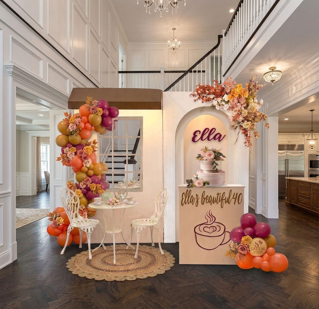 Coffee shop themed balloon decor in a mustard, orange, and burgundy color palette, with 2 panels and a garden table and 2 chairs set. decorated with balloon garland and flowers. Oregon from Salem to portland and nearby cities.
