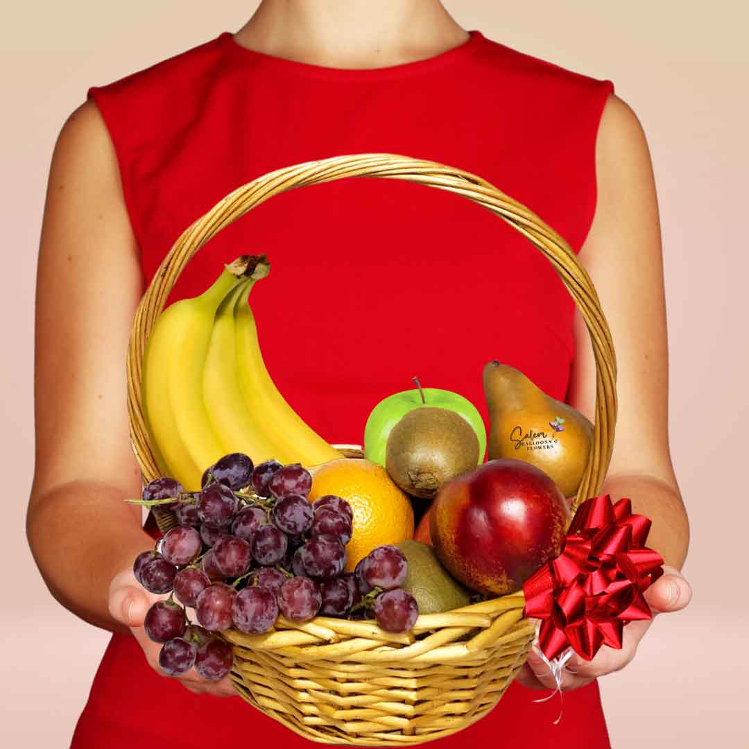 Woman holding a Brown basket filled with bananas, grapes, kiwis, pears, orange and nectarines.  Decorated with a big bow. Fruit baskets Salem Oregon and nearby cities.