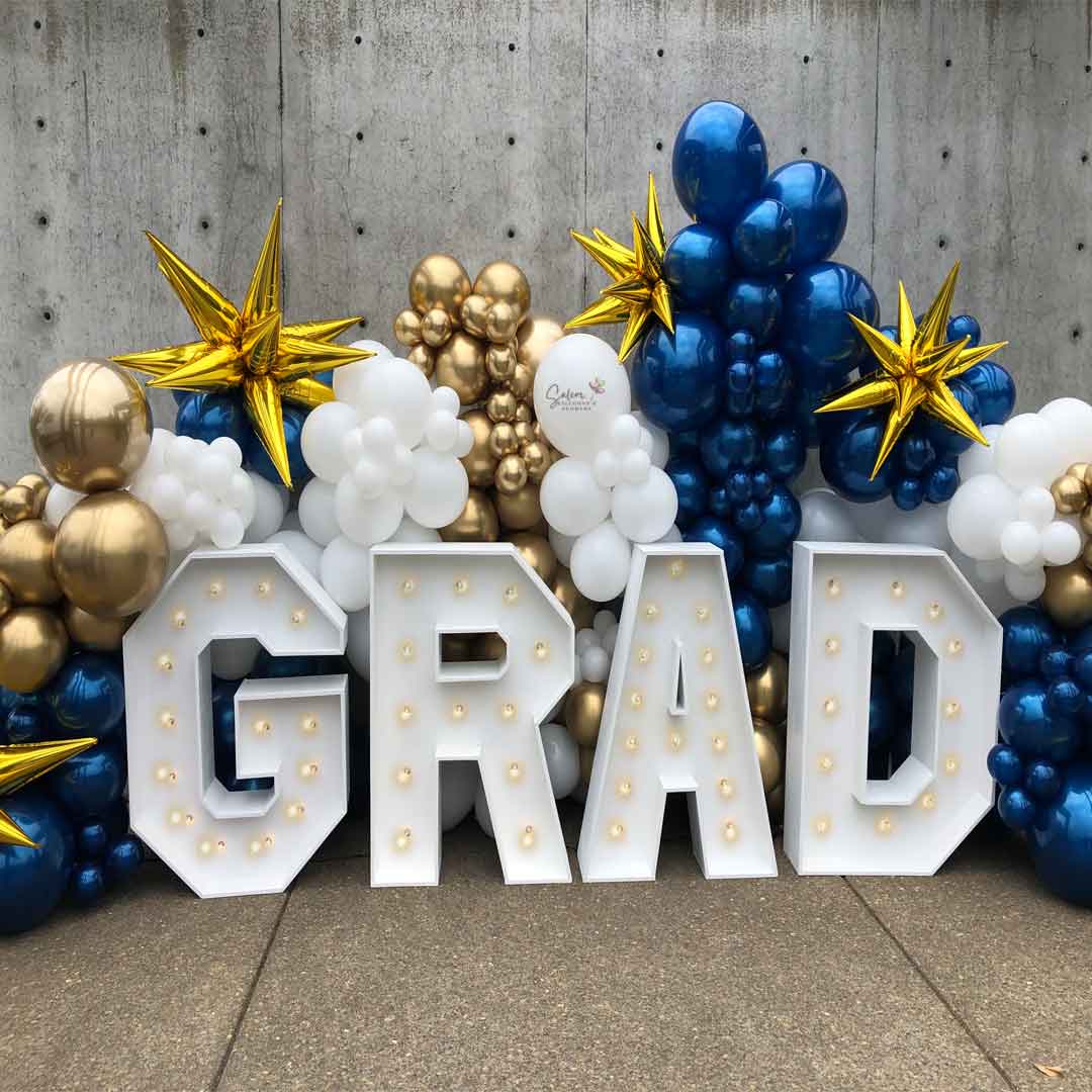 Front porch decorated with a Grad Balloon decor display. Featuring a GRAD light up marquee letters nested in a zaphire blue, gold and white balloon wall. Salem Oregon Balloon decor and marquee letters rental