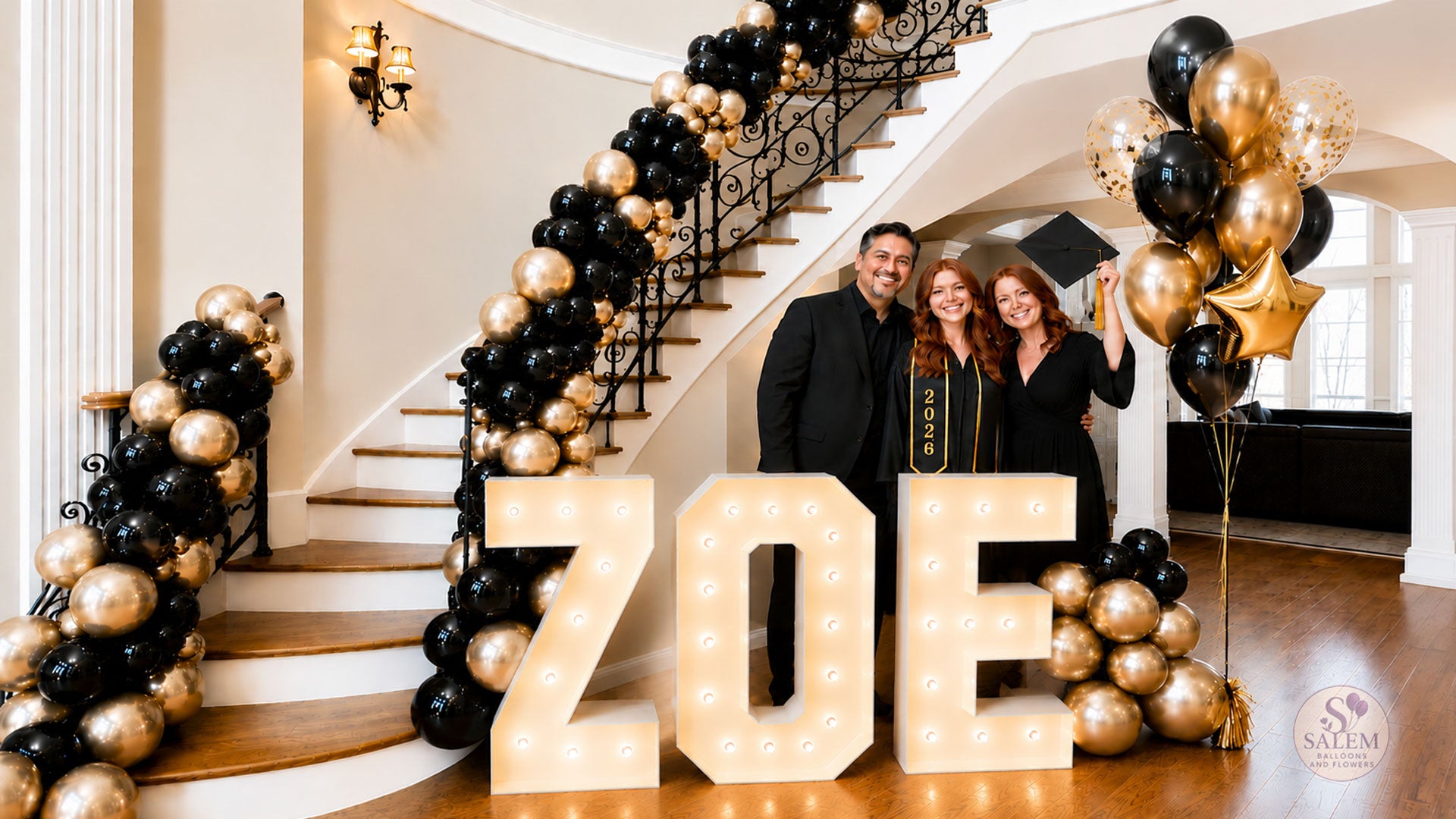 Luxury graduation party decorations in Salem Oregon featuring illuminated marquee letters, black and gold balloon garland staircase installation, and custom balloon decor by Salem Balloons and Flowers.