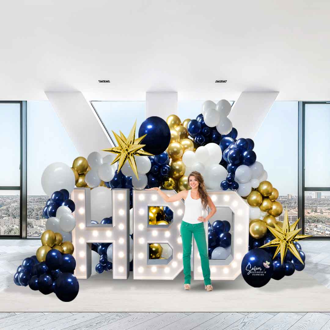 A young girl standing in front of a set of Light-up HBD Marquee letters surrounded by balloon garlands in navy blue, gold and white. Salem Oregon Balloon decor.