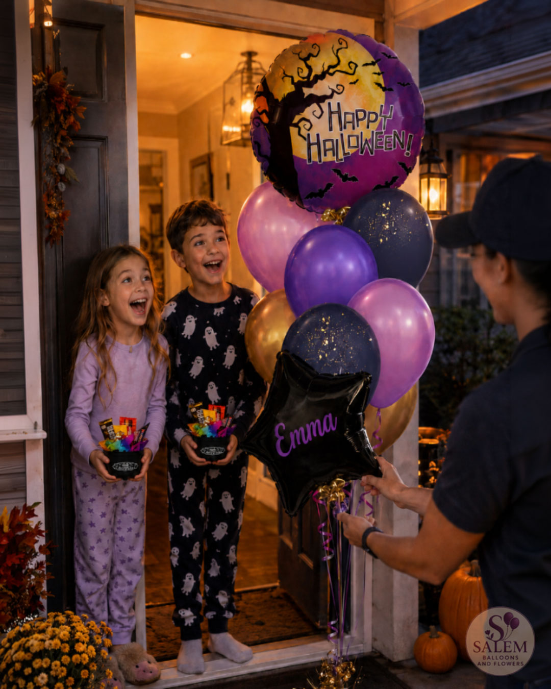 Two kids and an adult stand at a front door holding Halloween-themed balloons and candy baskets. The balloons include a purple 'Happy Halloween' foil balloon, lavender and dark blue balloons, a black personalized star balloon with the name 'Emma' in purple script, and a gold balloon with a spider graphic with a Salem Balloons and Flowers logo at the right bottom corner.