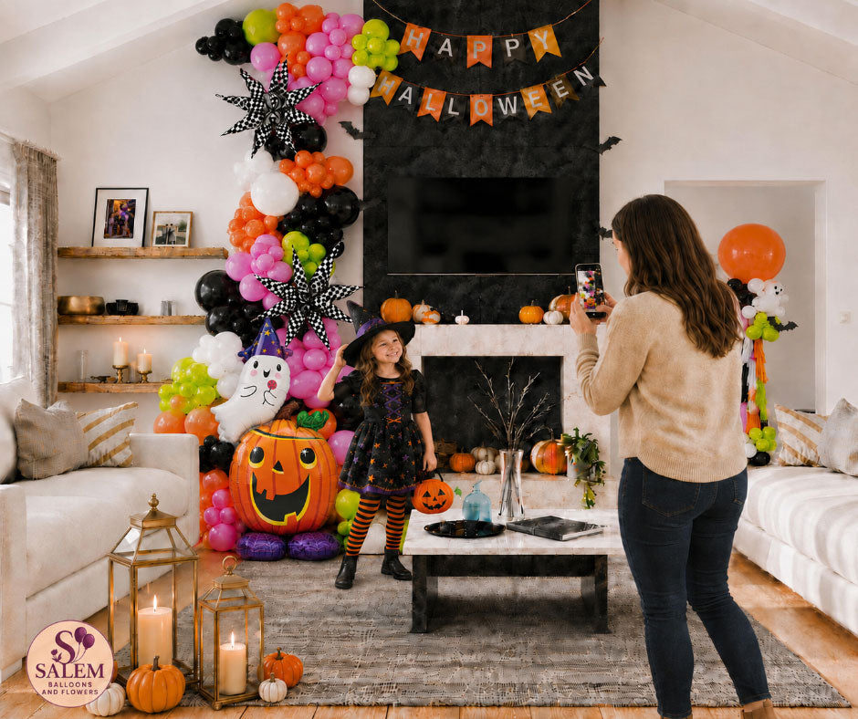 Girl in a witch costume posing beside colorful Halloween balloon décor while her mother takes a photo in a decorated Salem, Oregon home.