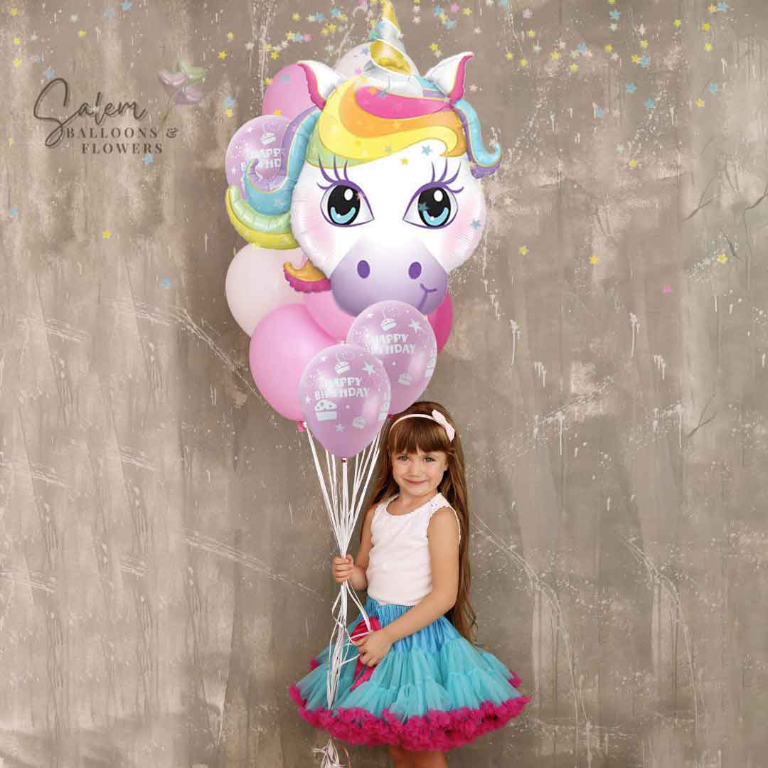 Little girl holding a large helium balloon bouquet with a large unicorn balloon in pastel colors. Balloon delivery in Salem Oregon and nearby cities.
