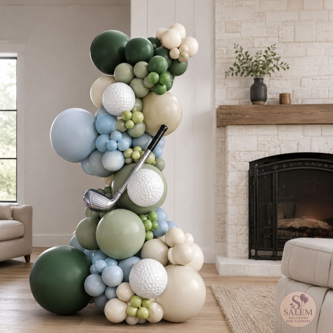 Golf themed balloon garland for a Hole in one themed standing on a living room in a green, cream and light blue color palette. Ideal for baby shower or 1st birthday by Salem Balloons and Flowers