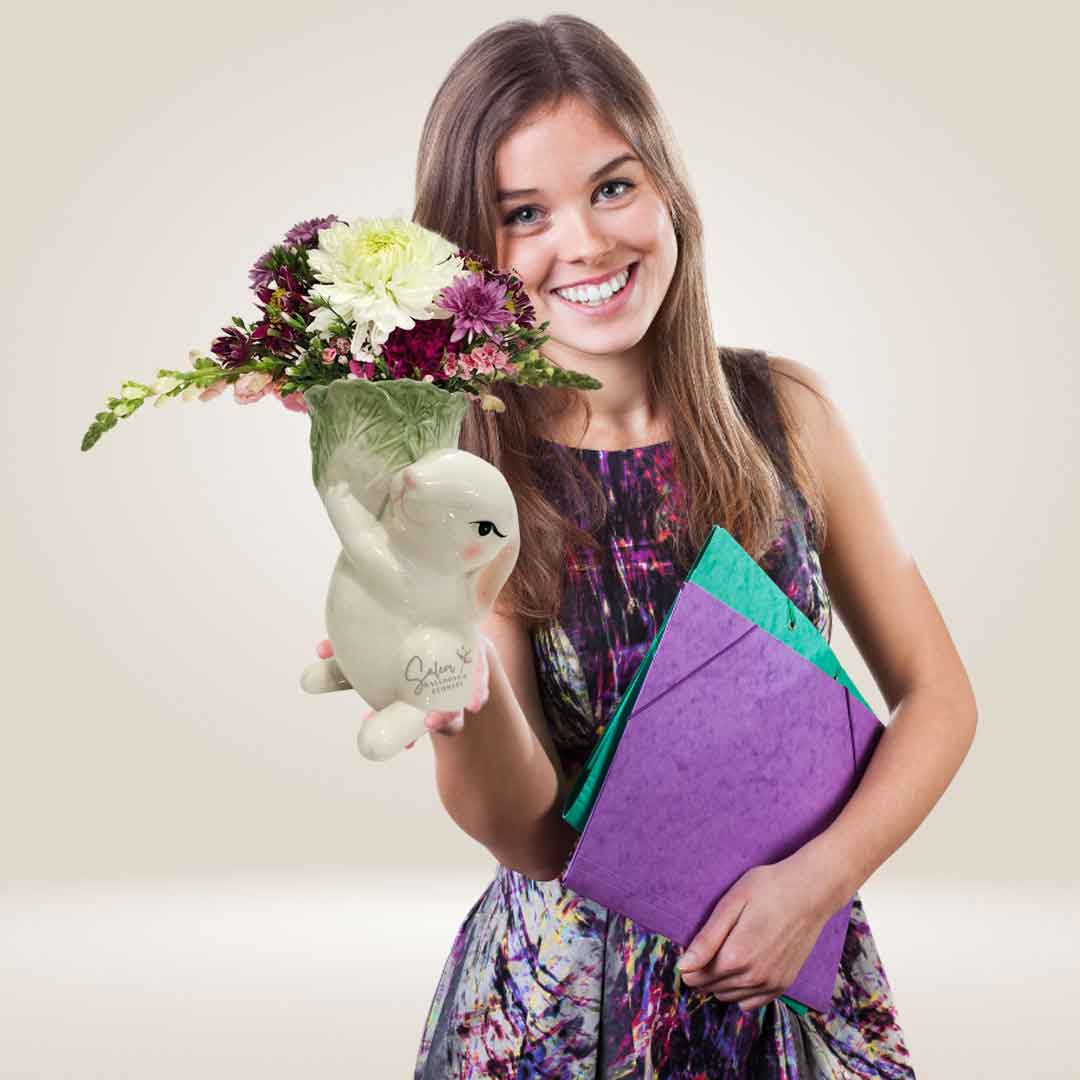 A young girl holding a charming ceramic vase in the shape of a bunny, carrying a Roman lettuce vase filled with vibrant and fresh blooms. Delivery in Salem-Keizer Oregon .