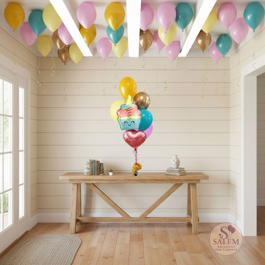 Colorful balloons with a smiley face ice cream mylar balloon on a wooden table against a light wood paneled wall with a set of helium balloons in matching colors decorating the ceiling. Balloon delivery. Oregon.