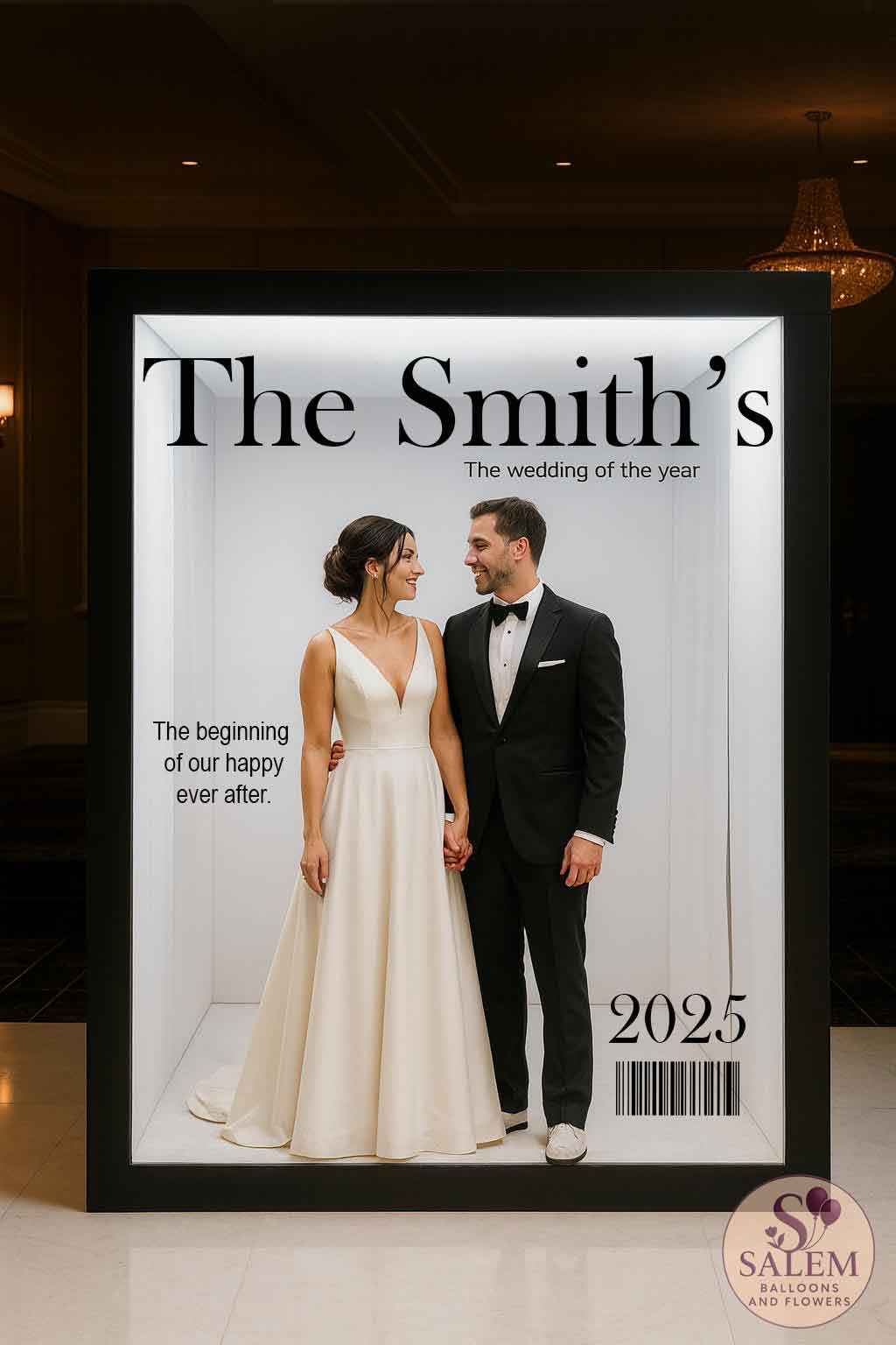 A newlywed couple holding hands inside of a magazine cover photo booth with a large sign spelling "The Smith's" and smaller signs spelling "The wedding of the year", The beginning of our happy ever after.", 2025, and a barcode. Wedding rentals. Oregon.