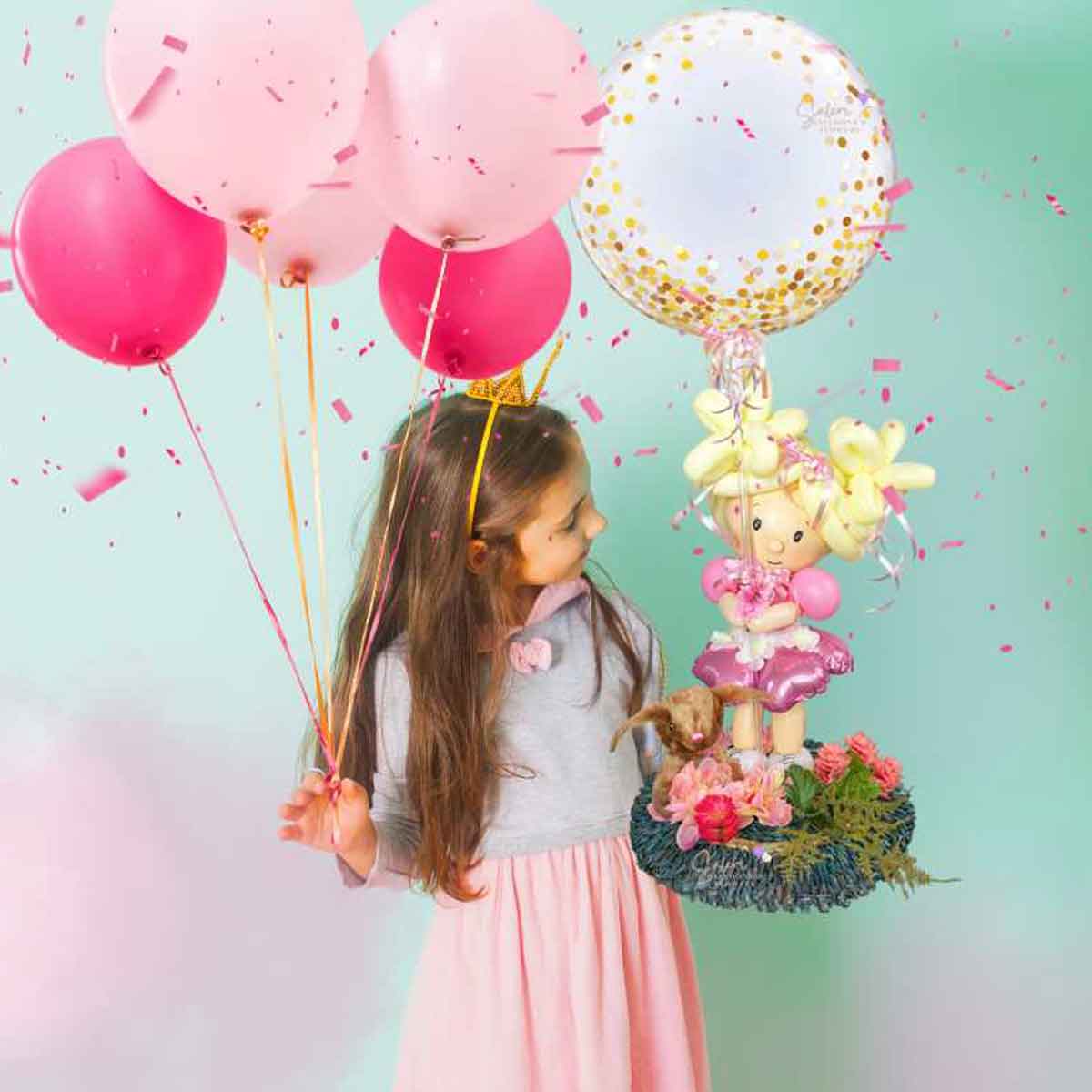 balloon doll with messy buns hair holding a bubble balloon, among flowers and a plush. Table centerpiece.  Approx. 3 Ft tall. Balloon delivery Salem Oregon.