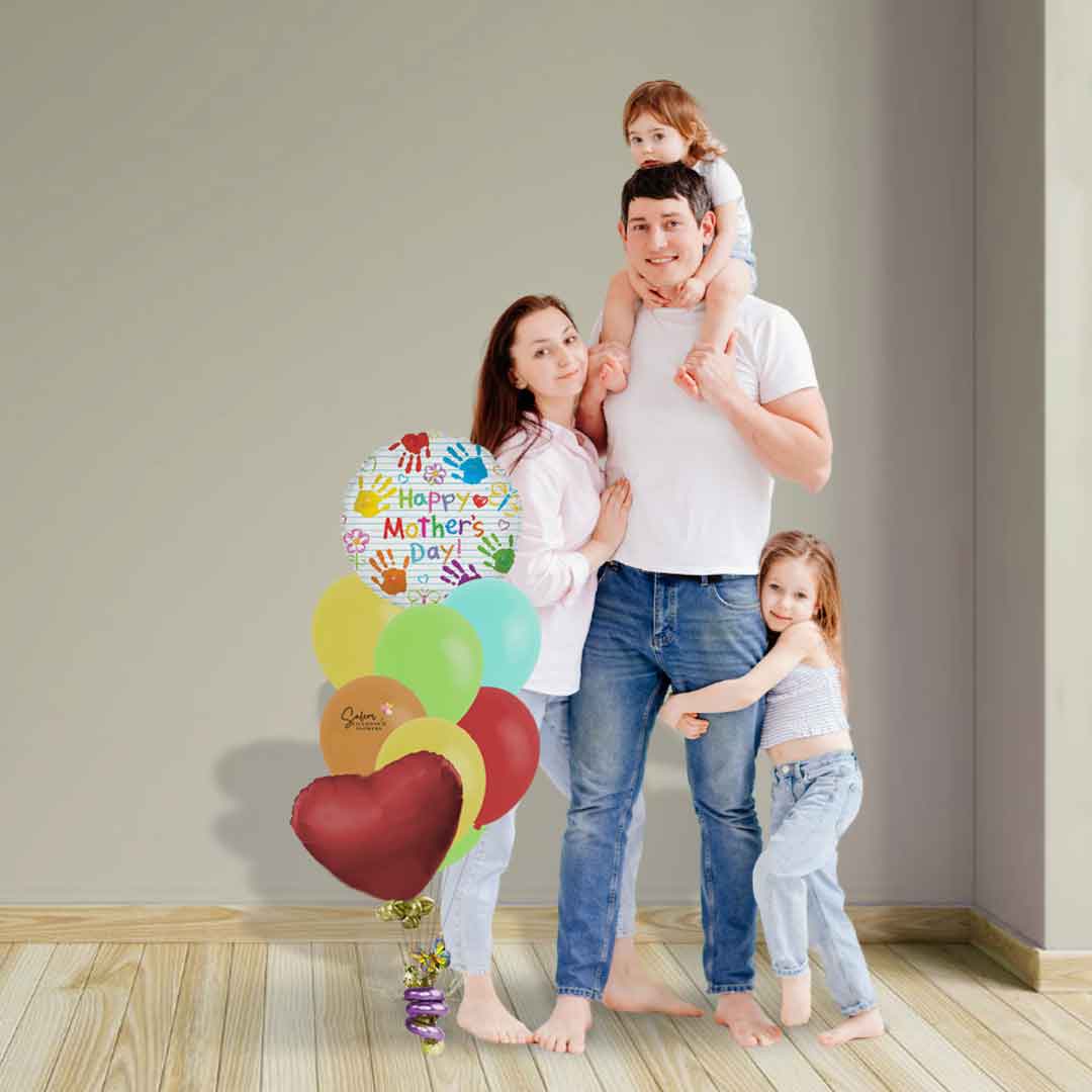 A family standing next to a Mother's Day Balloon Bouquet, featuring a mylar balloon with little handprints and a  