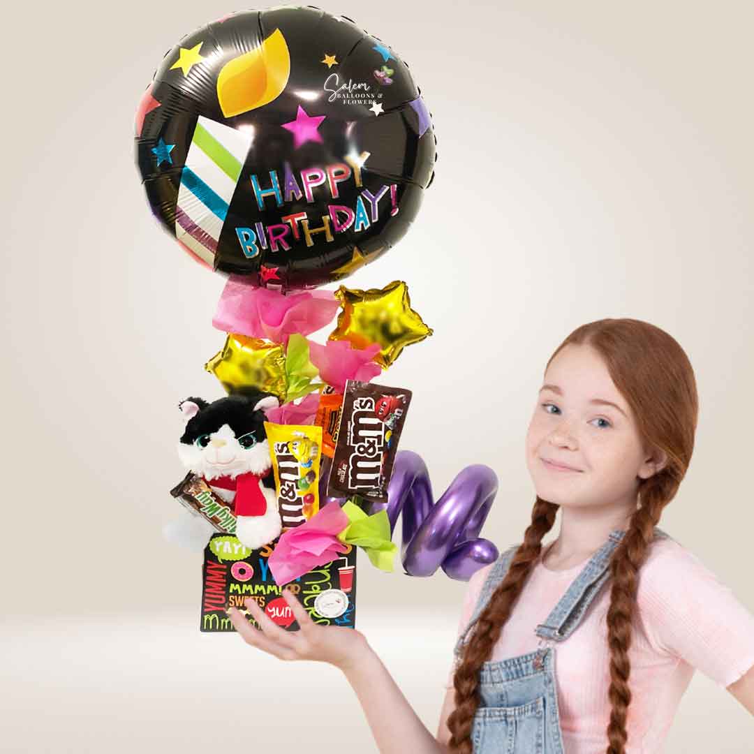 A girl holding a Candy box balloon bouquet with plush and candy and chocolates. Salem Oregon balloon delivery.