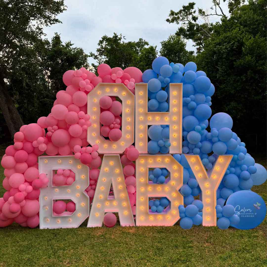 An "OH Baby" Gender Reveal Marquee Letter Display. 3ft Marquee letters nested into a pink and blue balloon wall in exteriors.  Balloon Decor and rentals in Oregon.