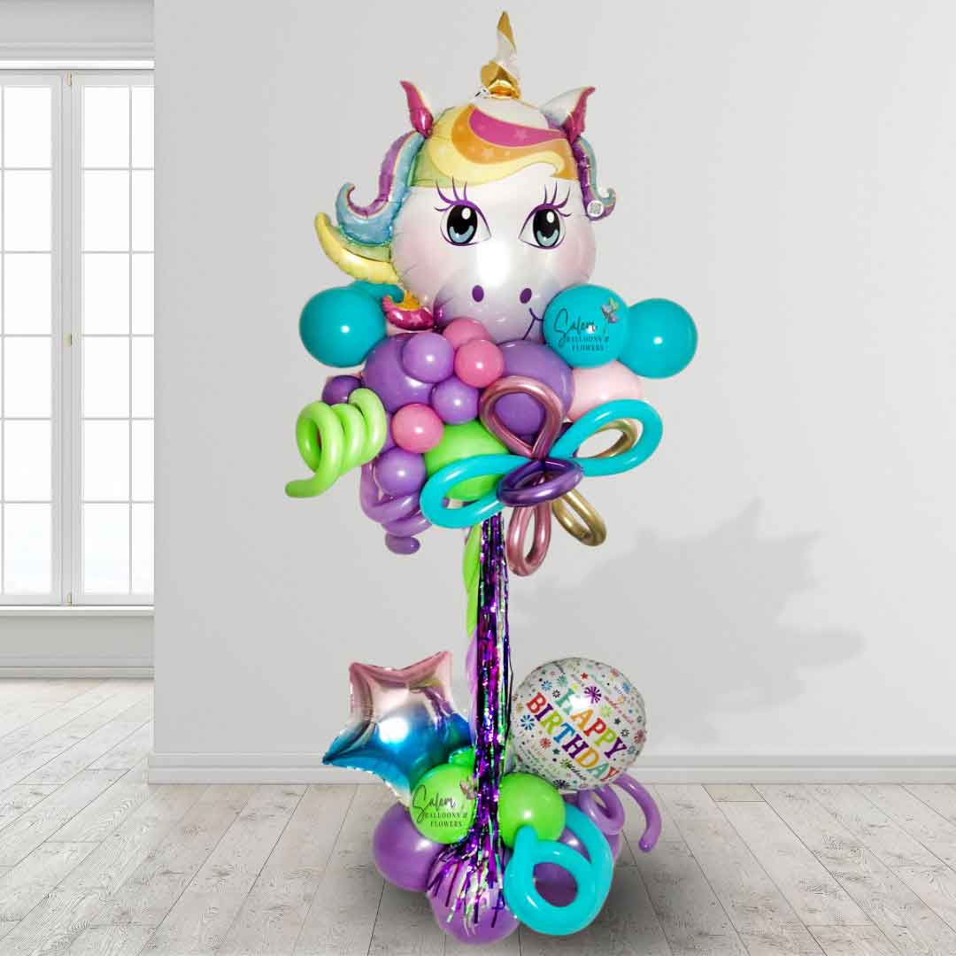 A Unicorn themed Balloon Column. In vibrant pastel colors standing in front of a white wall. Featuring a large Unicorn head as topper. Oregon Balloon Decor