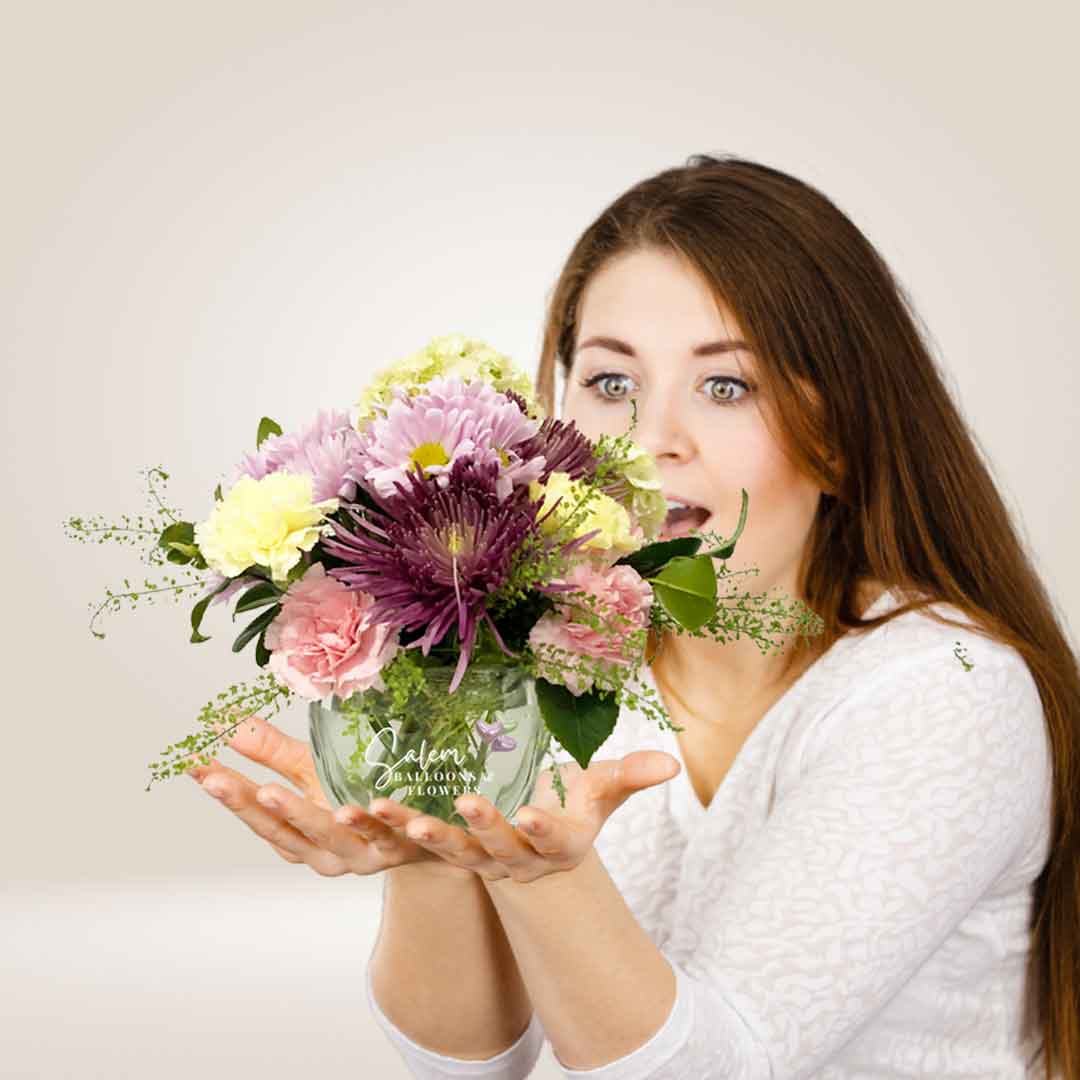 A young girl holding Fresh flowers in a square glass vase in her hands. Salem Oregon flower delivery.