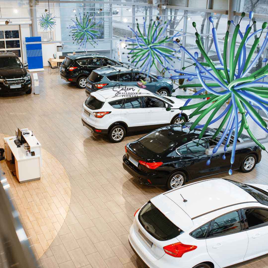 Car Dealership ceiling decorated with Pom-Poms Ceiling balloon decorations in blue and green. Salem Oregon balloon decor.