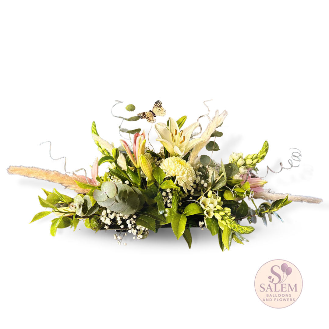 Floral arrangement with greenery, lily flowers, snapdragon flowers, curly twigs, and a butterfly with small pampas grass on a white background, featuring the Salem Balloons and Flowers logo. Flower delivery in Salem Oregon and nearby cities.