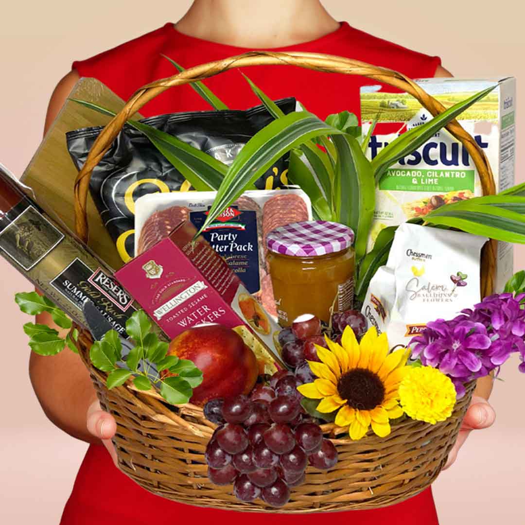 woman holding a gourmet treats gift basket with an assortment of meats, cheeses, crackers, fruits ans a natural plant. Delivery in Salem Oregon and nearby cities.