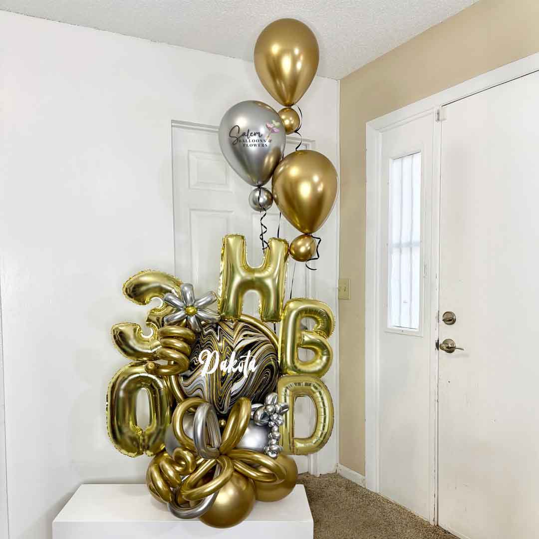 Gold and silver balloons spelling 'Happy Birthday' in a room. With a marbled orbz balloon in gold, silver and black. Oregon 
Balloon delivery.