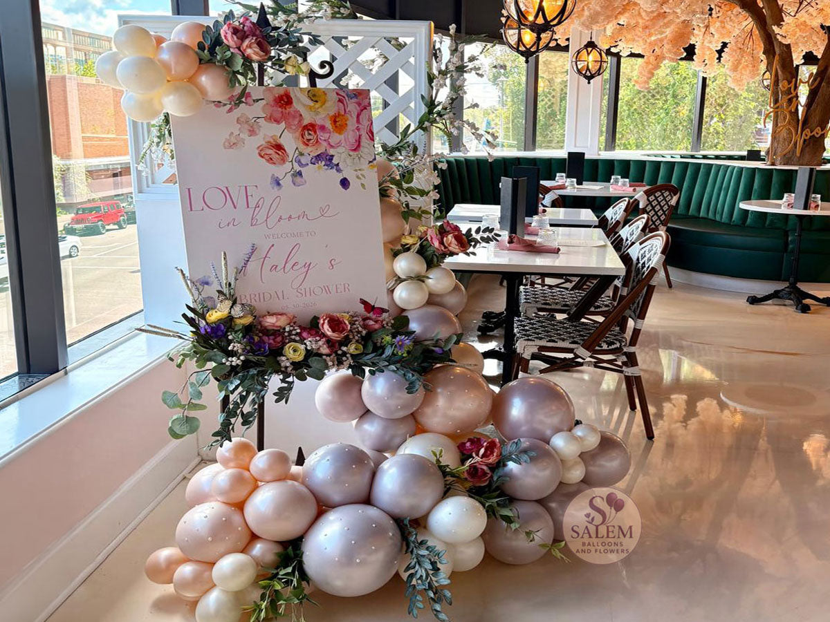 Balloon garland on an easel welcome sign. decorated with flowers, pearls, and butterflies at the clink french restaurant in Salem Oregon by Salem Balloons and Flowers.