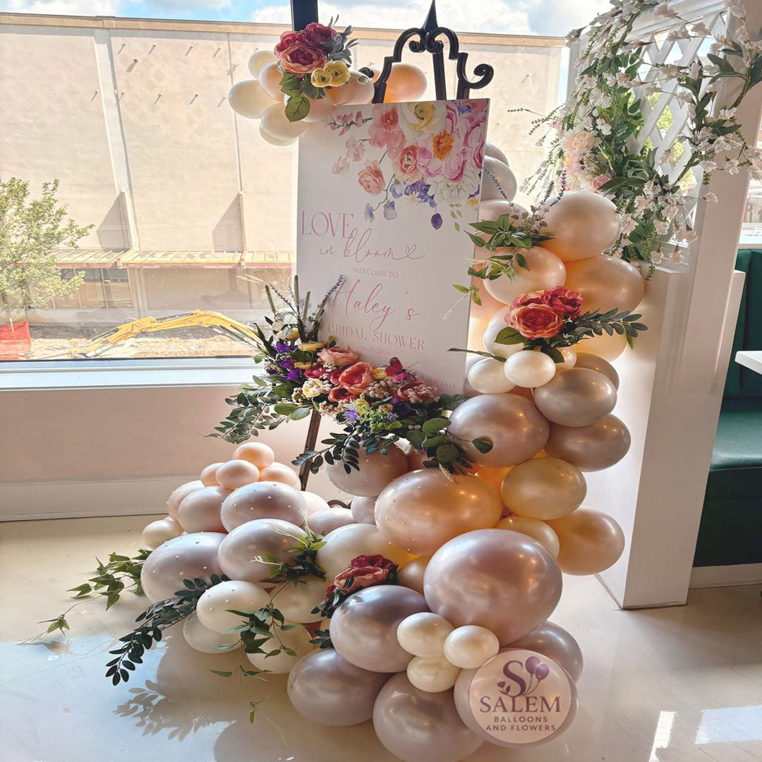 Bridal shower welcome sign with luxury balloon garland and floral accents at The Clink in Salem, Oregon. Love in Bloom themed event decor featuring custom signage, organic balloons, and elegant floral styling for weddings and bridal showers in the Willamette Valley.