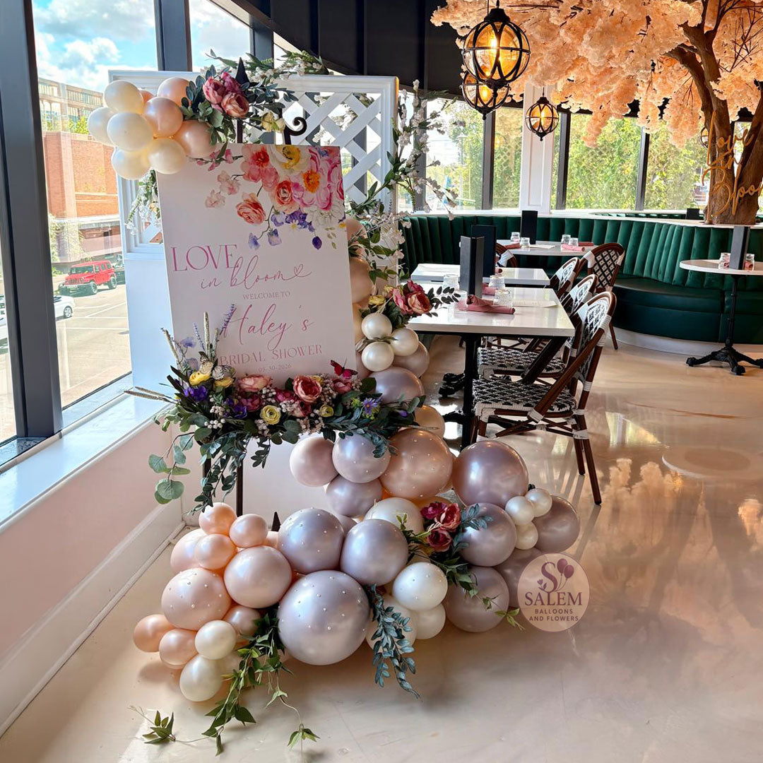 Bridal shower welcome sign with luxury balloon garland and floral accents at The Clink in Salem, Oregon. Love in Bloom themed event decor featuring custom signage, organic balloons, and elegant floral styling for weddings and bridal showers in the Willamette Valley.