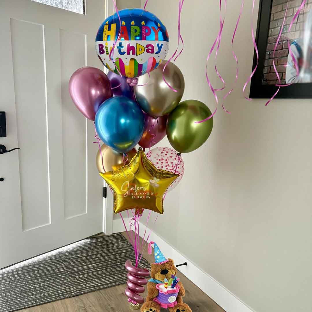 Colorful birthday balloons with a teddy bear and streamers on a door step. Balloon delivery. Oregon.