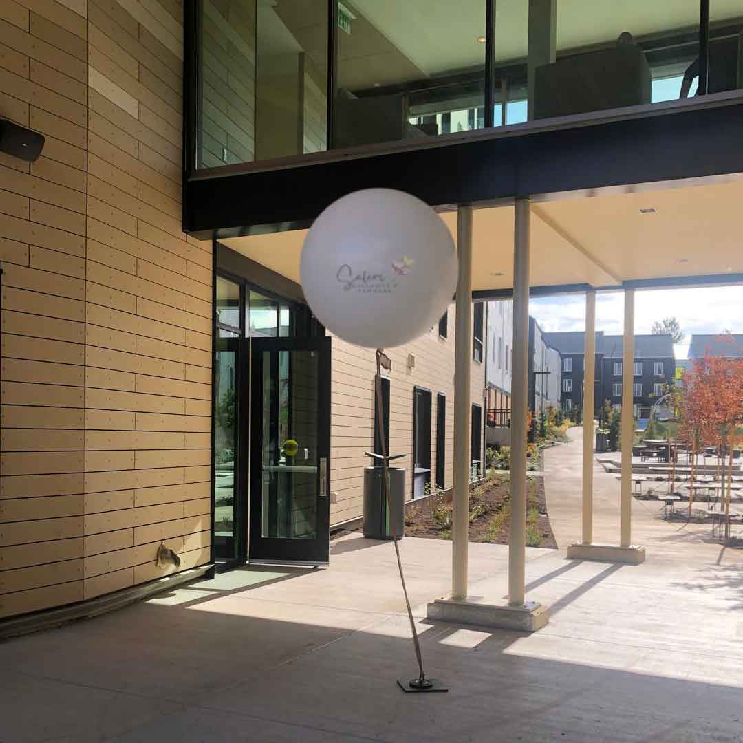 A umbo balloon  in beige floating in front of a building. Oregon Balloon decor.